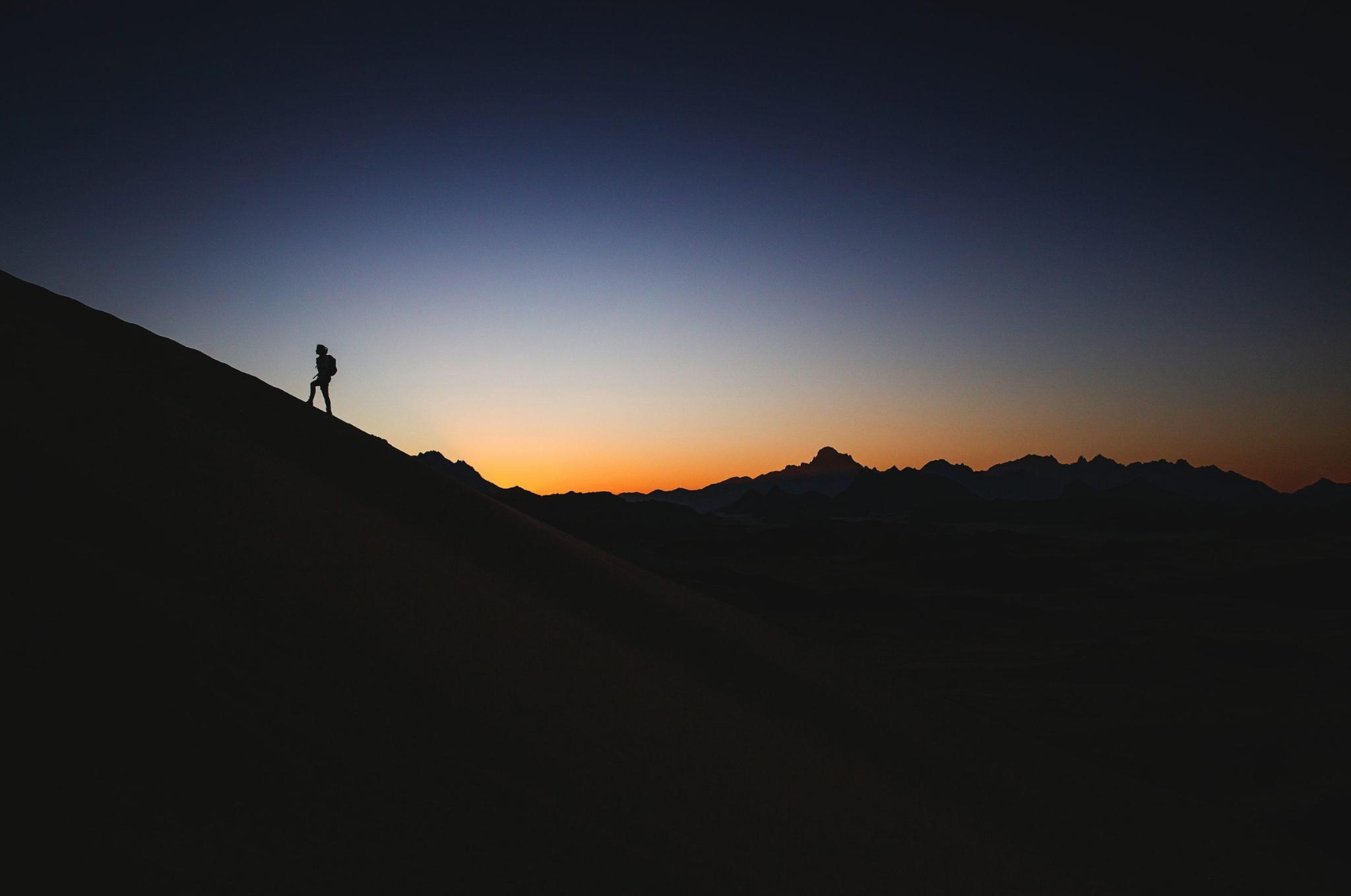 A hiker crossing a mountain ridge at sunset