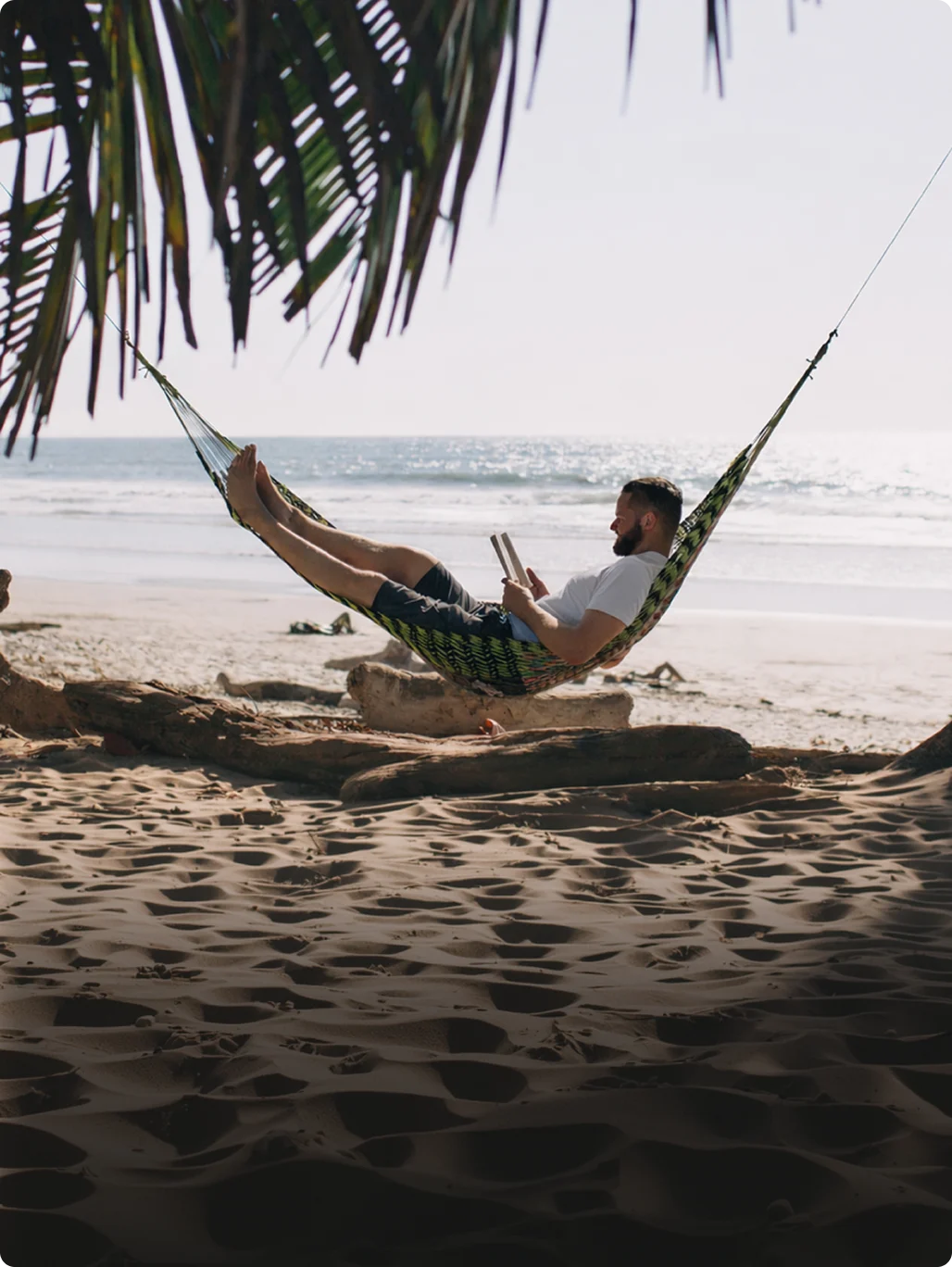 A man relaxing in a hammock beside the sea